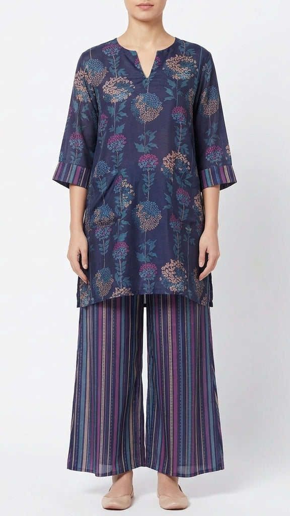 Woman wearing a navy blue floral patterned top and striped pants on a white background